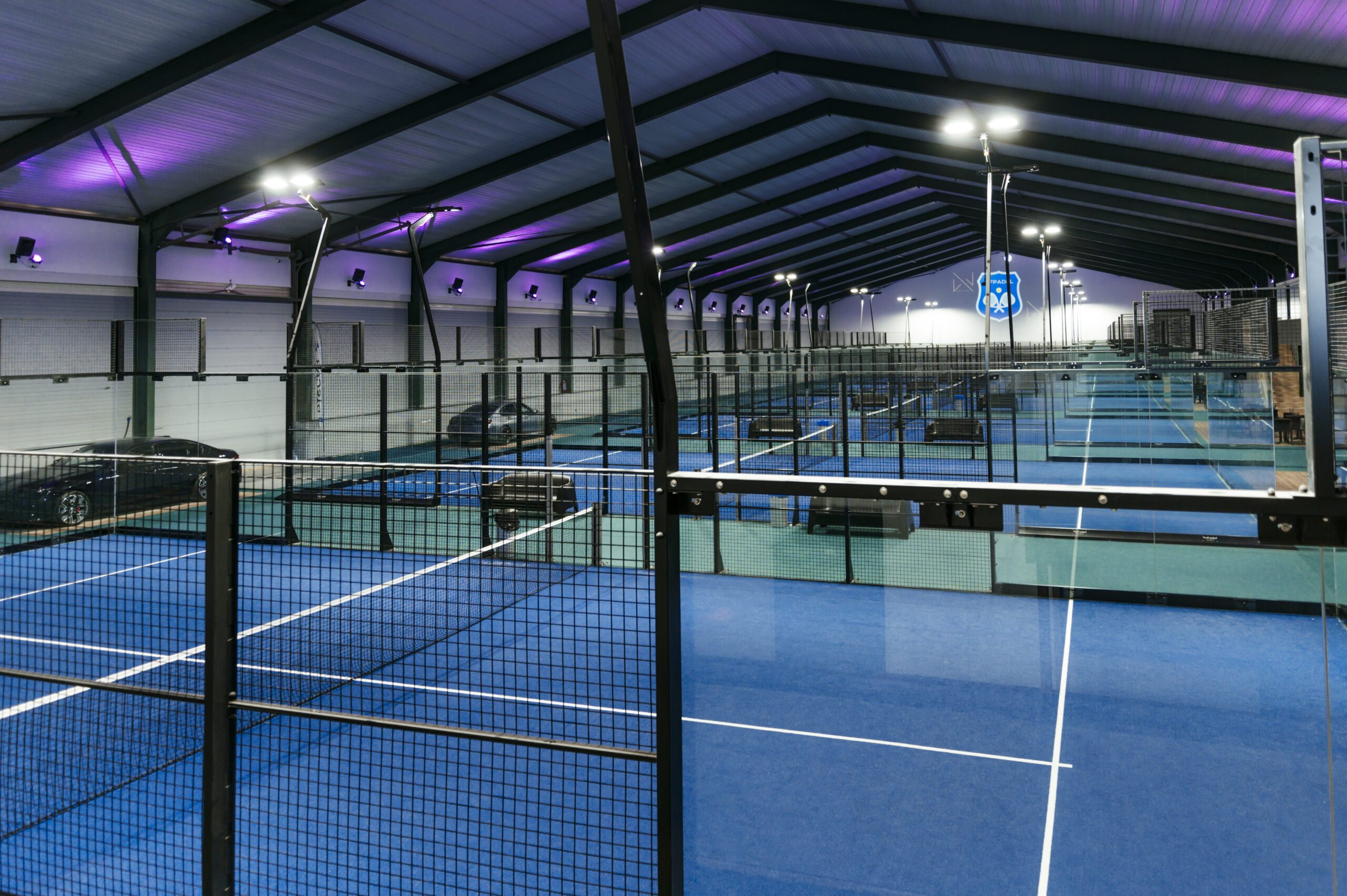 Un terrain de padel du Wel Padel, avec le logo du club sur la vitre de fond